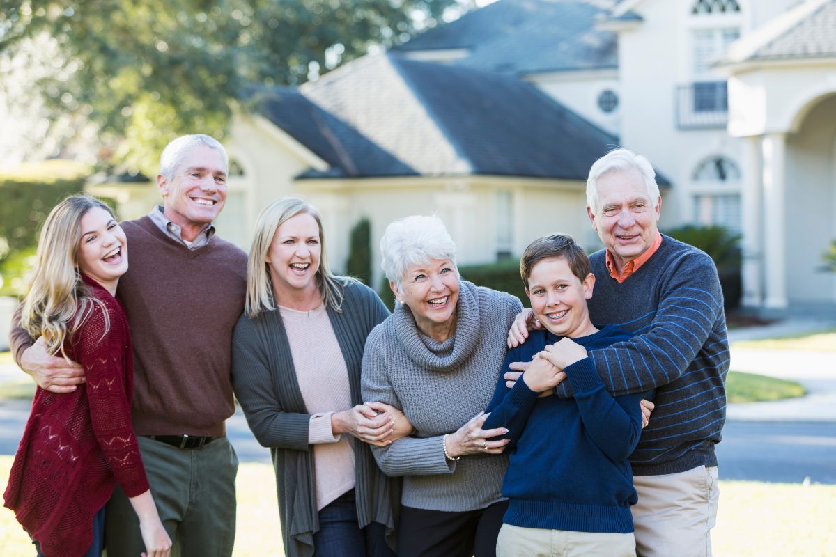 Happy multigenerational family poses in front of a home
