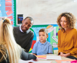 Two parents and a child having a parent teacher conference with a teacher in an elementary school