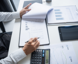 Man at a desk looking at financial records with a calculator
