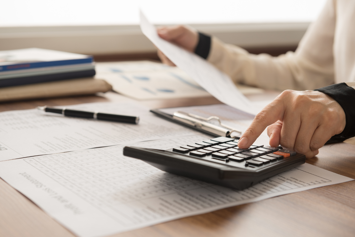 person at desk with papers, pen, and calculator