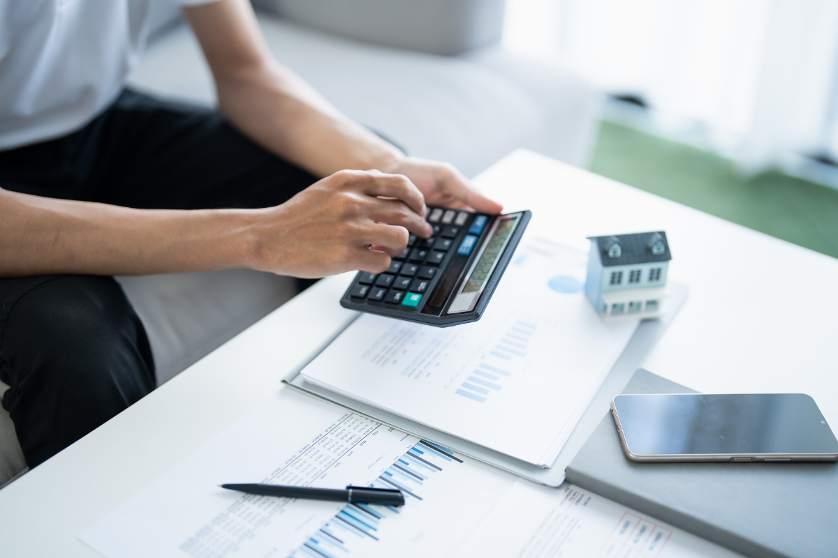 person using calculator over a desk with papers on it