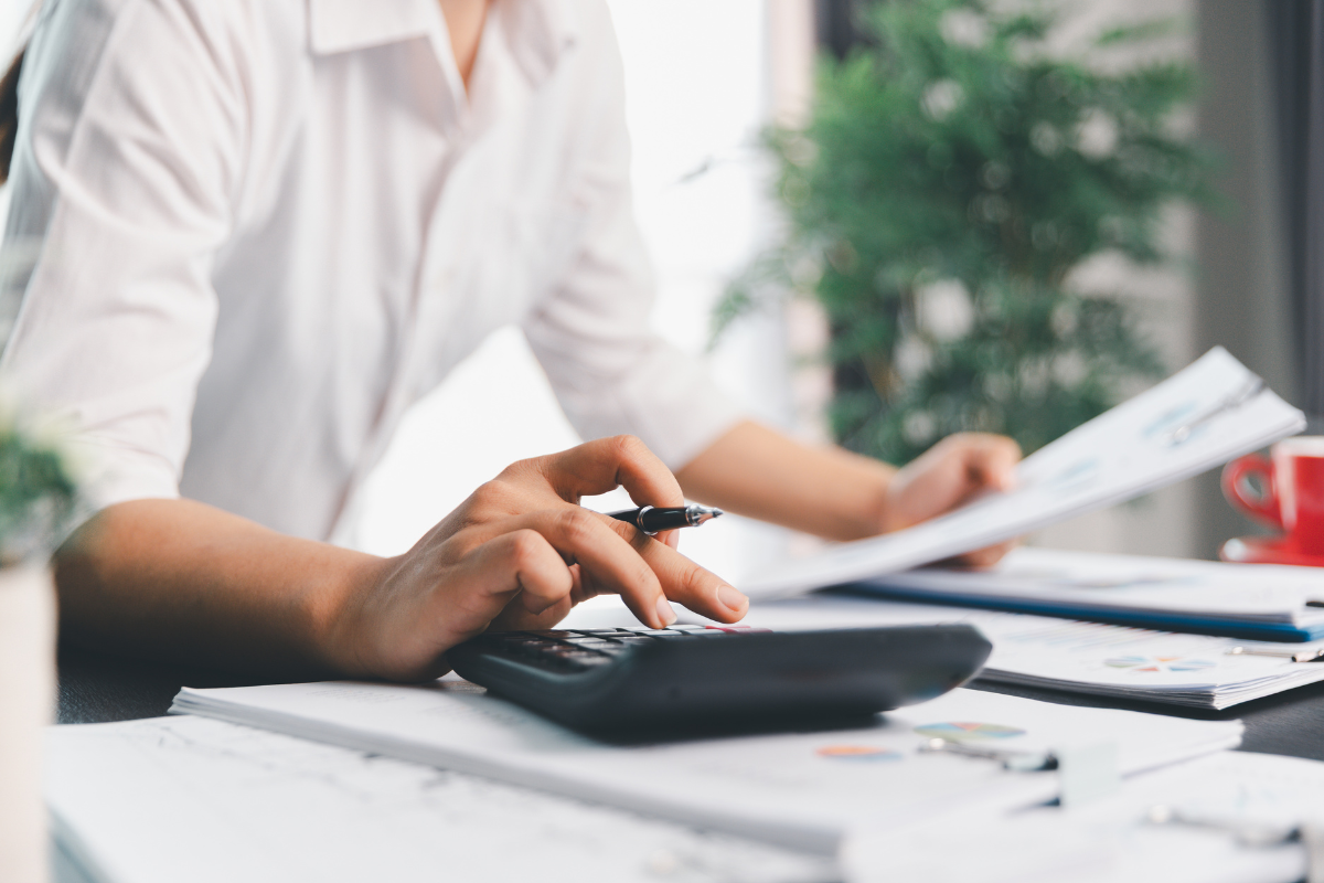 person at a desk with papers typing into a calculator