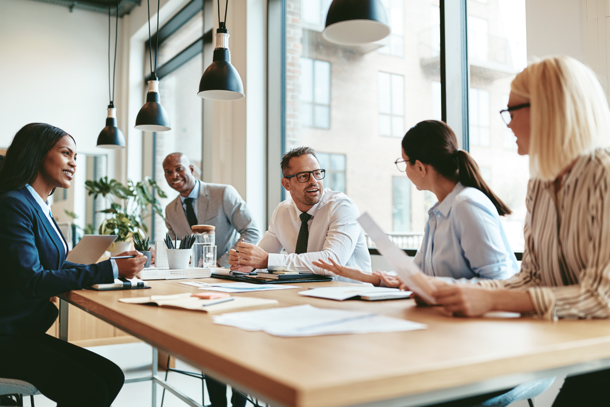 group of business people sitting around a table with papers talking