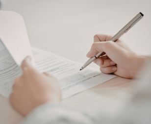 person using a pen to sign off on a few papers