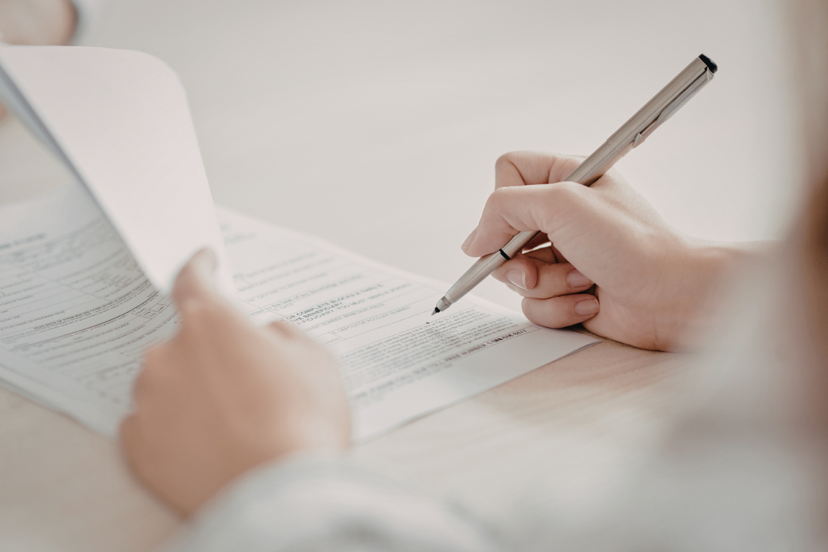 person using a pen to sign off on a few papers