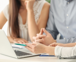 couple sitting with another person showing them documents and a laptop
