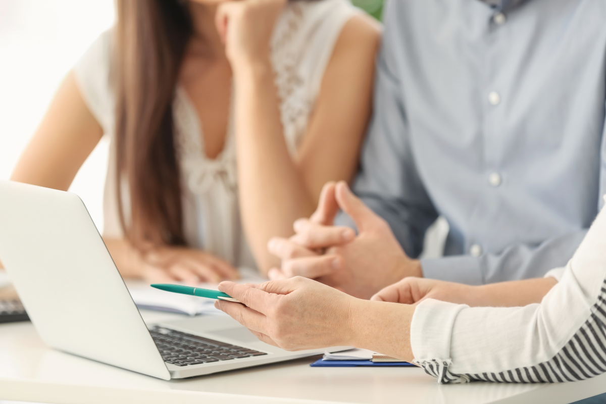couple sitting with another person showing them documents and a laptop