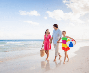 family walking on the beach with daughter carrying a beach ball