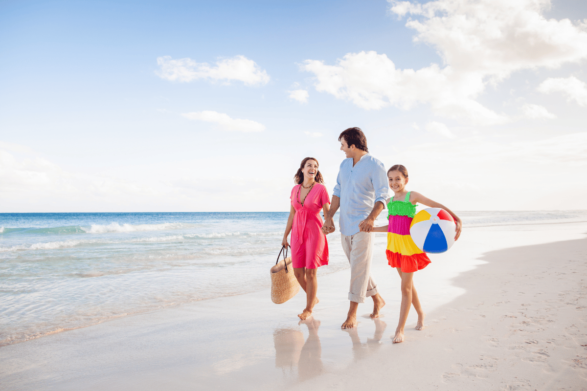 family walking on the beach with daughter carrying a beach ball