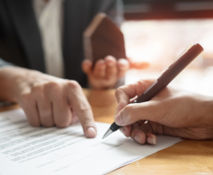attorney meeting with client showing them paper agreements and where to sign